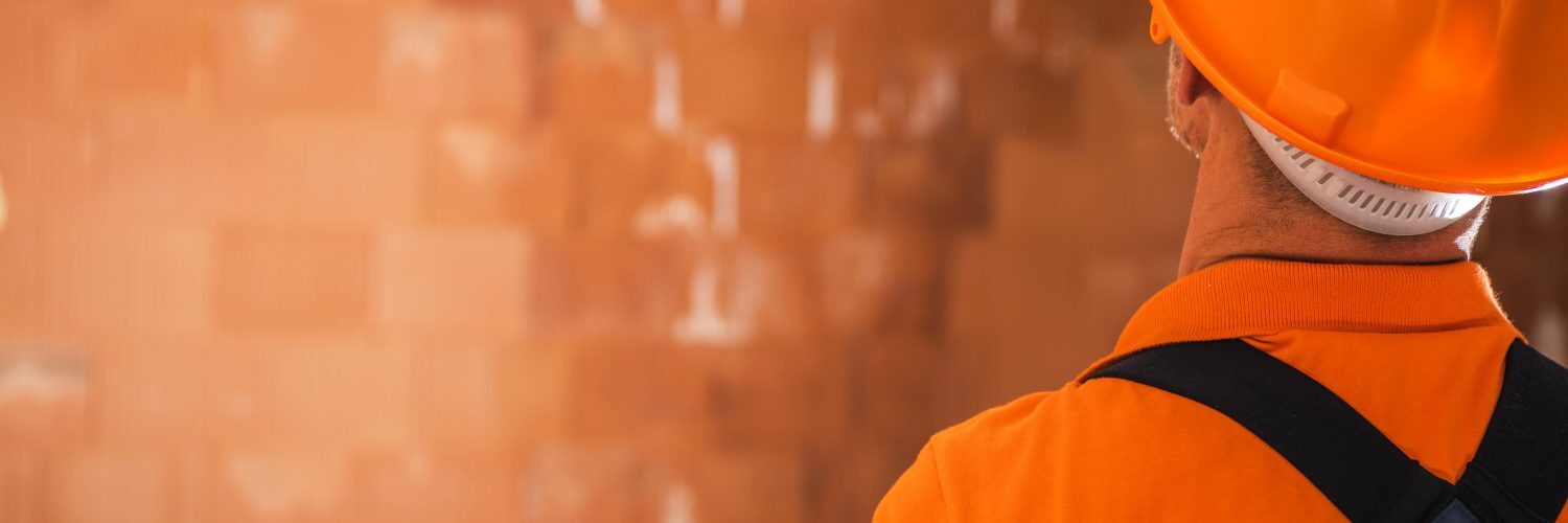 A man wearing an orange hard hat and overalls, ready for work.